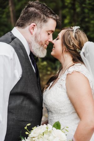 A romantic wedding portrait showing a tender moment between newlyweds against a natural backdrop.