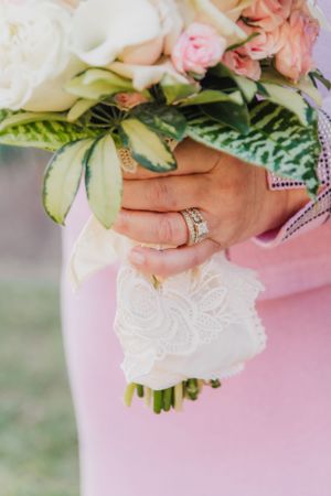 Close up of bridal bouquet with white and pink flowers, showcasing wedding ring detail.