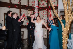 Wedding celebration scene with guests throwing confetti as couple celebrates on dance floor.