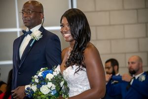 Elegant wedding ceremony with couple at altar holding blue and white floral bouquet.