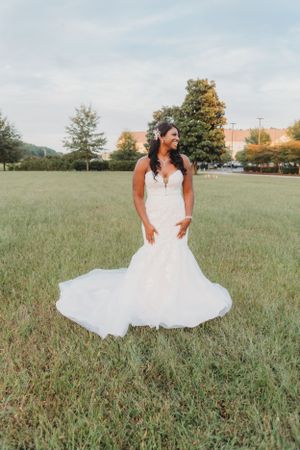 Stunning mermaid wedding dress with sweetheart neckline photographed in an open field at sunset.