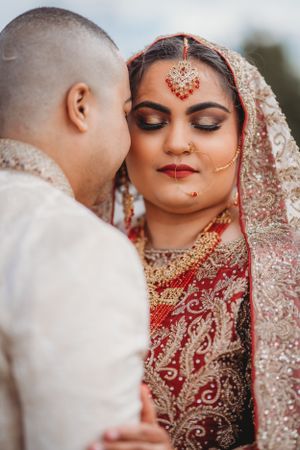 Traditional South Asian wedding couple sharing intimate moment in formal attire.