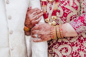 Detailed shot of hands with mehndi designs against traditional South Asian wedding attire.