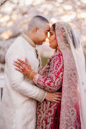 South Asian bride and groom share intimate moment in traditional wedding attire.