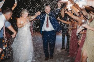 Wedding party celebrating with confetti shower during evening departure.