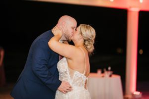 Couple sharing a romantic dance moment at an evening wedding reception with warm lighting.