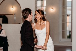 Candid wedding moment captured indoors with couple sharing joyful laughter.