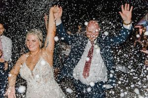 Joyful wedding celebration with guests showering newlyweds in white confetti.