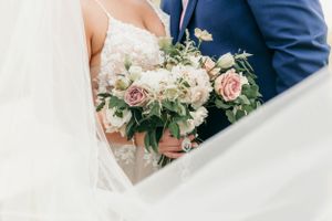 Close-up of blush and cream bridal bouquet against white wedding dress.