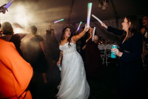 Wedding reception dance party with glowing LED sticks and atmospheric lighting.