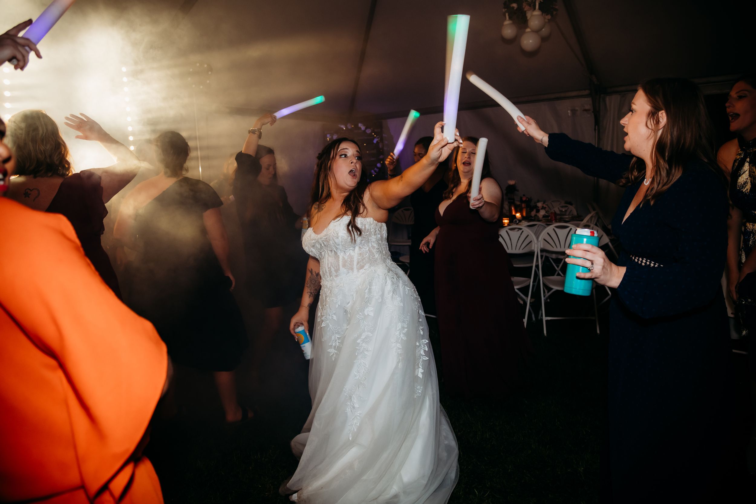 Wedding reception dance party with glowing LED sticks and atmospheric lighting.