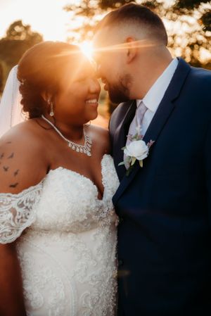 A romantic sunset wedding portrait with golden sunlight streaming between the couple.