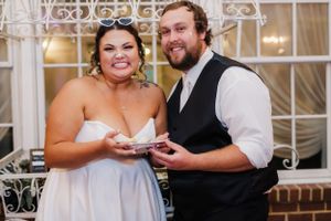 A newlywed couple shares a cake-cutting moment at their wedding reception.