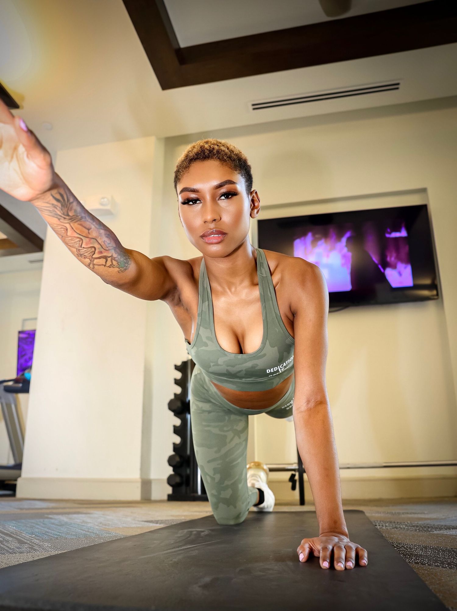Athlete performs a plank exercise on a gym mat while wearing gray athletic wear.
