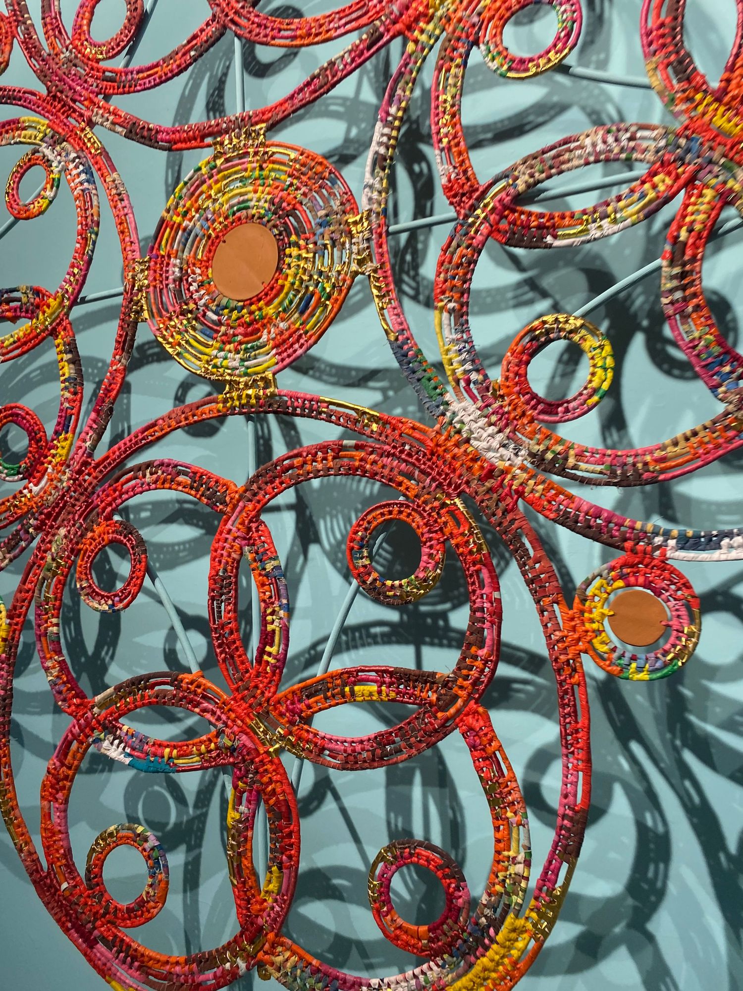 Intricate red and orange circular patterns creating symmetrical design on reflective surface.