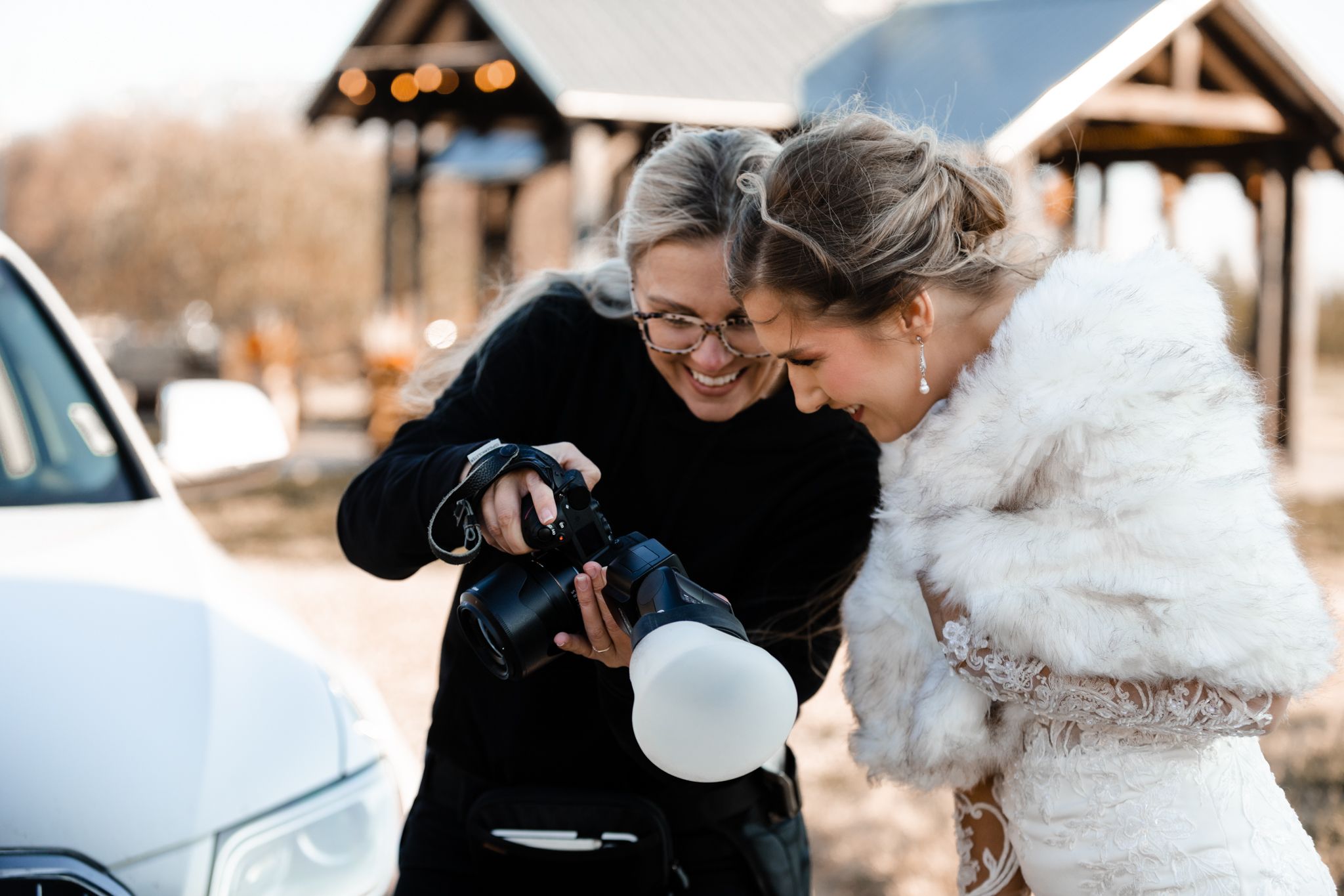 Two photographers sharing a candid laughing moment while reviewing photos.
