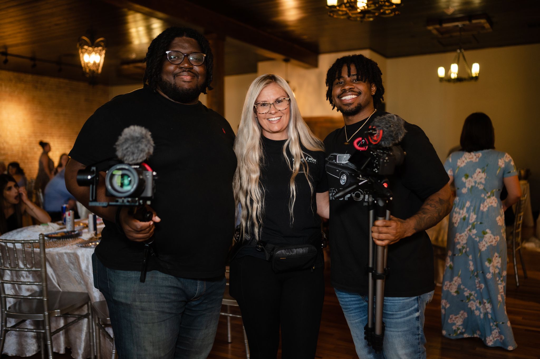 Professional photography team poses with their cameras at an elegant indoor venue.
