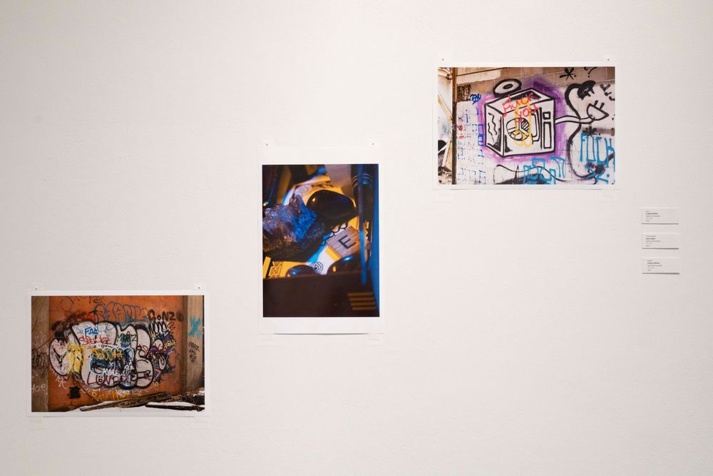 Collection of colorful street art and graffiti photographs arranged on gallery wall.