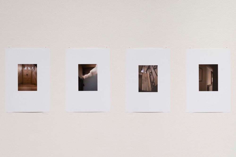 Four small sepia-toned photographs mounted in a row on a white gallery wall.