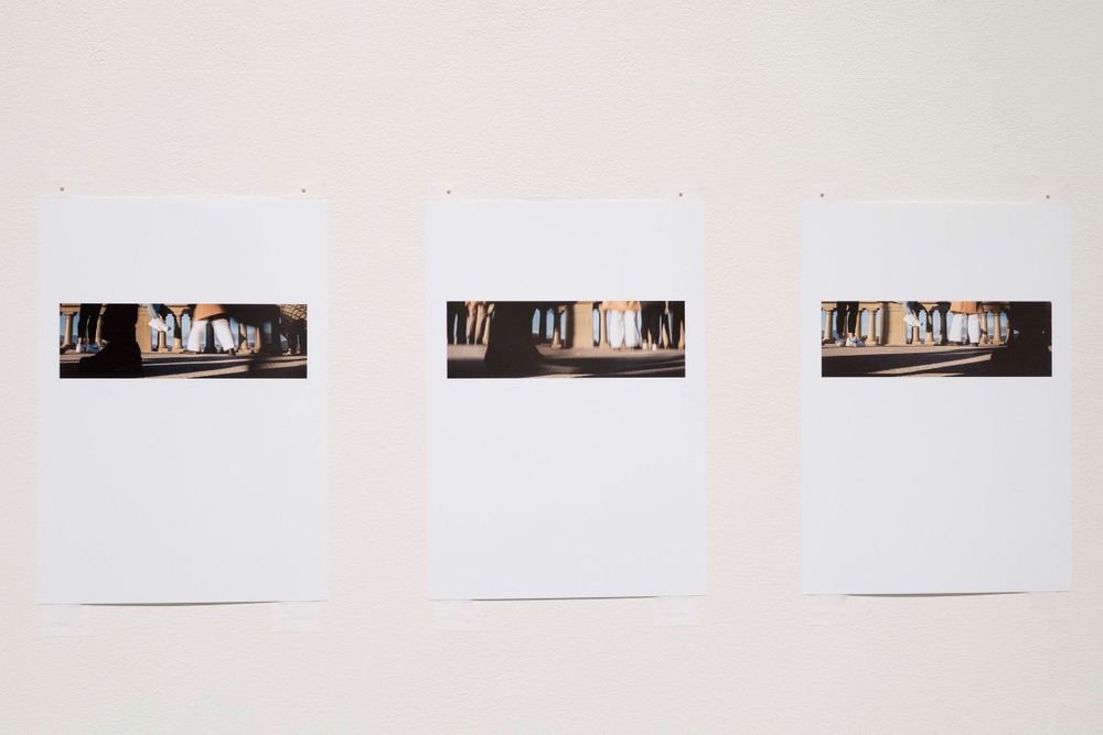 Three identical framed photographs displayed in sequence on gallery wall.