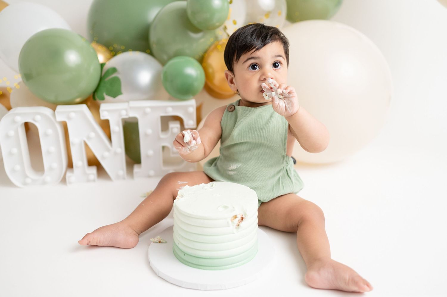 First birthday cake smash setup with mint green and gold decorations.