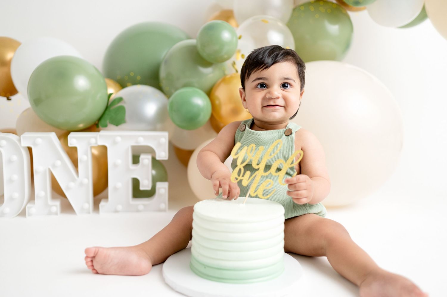 First birthday celebration with mint green cake and balloon arch decorations.