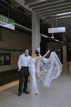 A bride and groom posing dramatically in a subway station with flowing veil.
