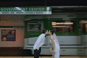 A romantic wedding photo at Government Center subway station with a passing train.