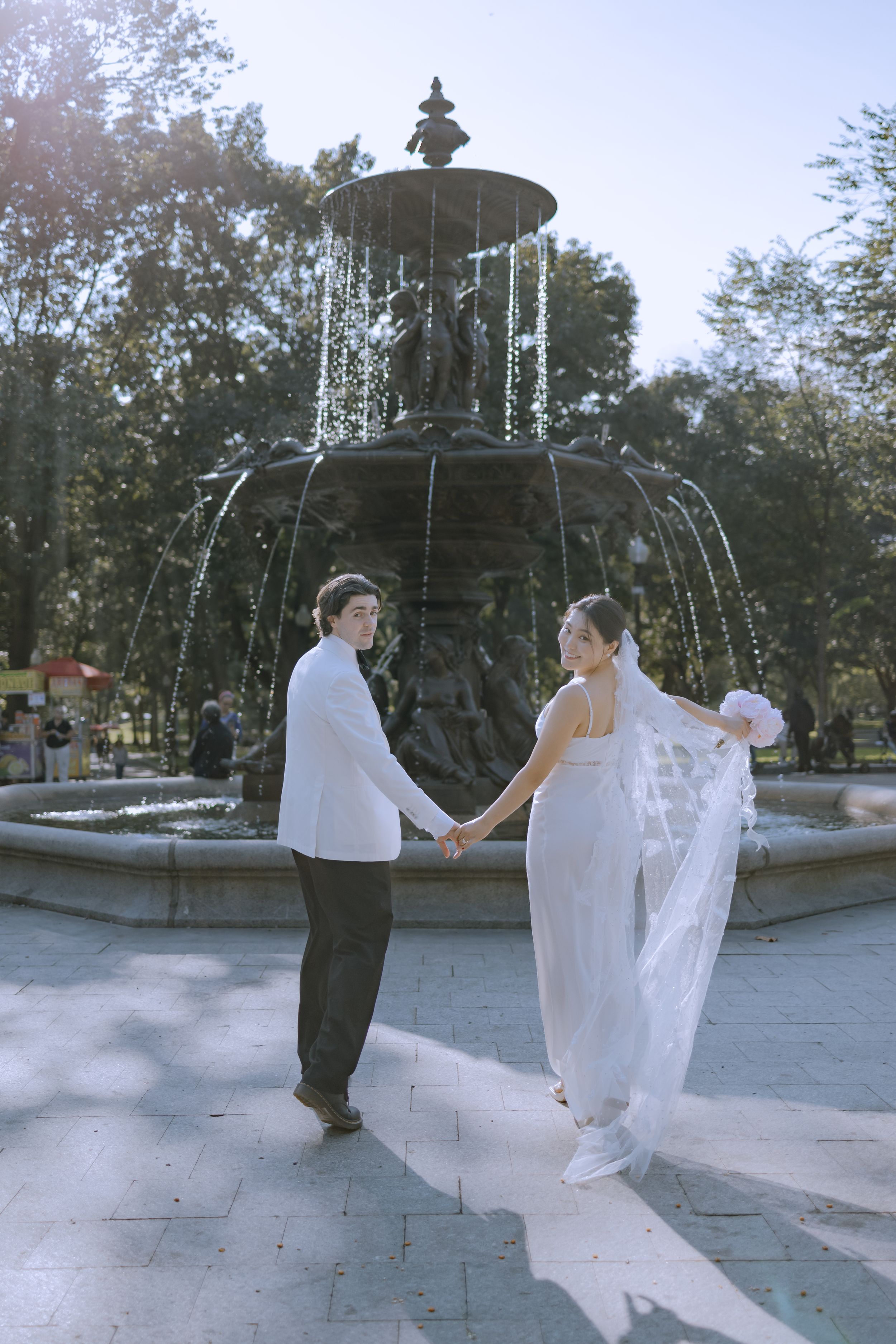 Couple dancing playfully by a fountain in a public park.