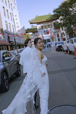 A wedding photo in Boston's Chinatown with traditional architecture and decorations visible.
