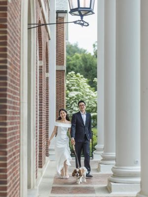 Elegant wedding portraits under white columns with a dog joining the couple.