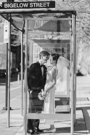 A black and white wedding photo of a couple standing in a phone booth under a Bigelow Street sign.