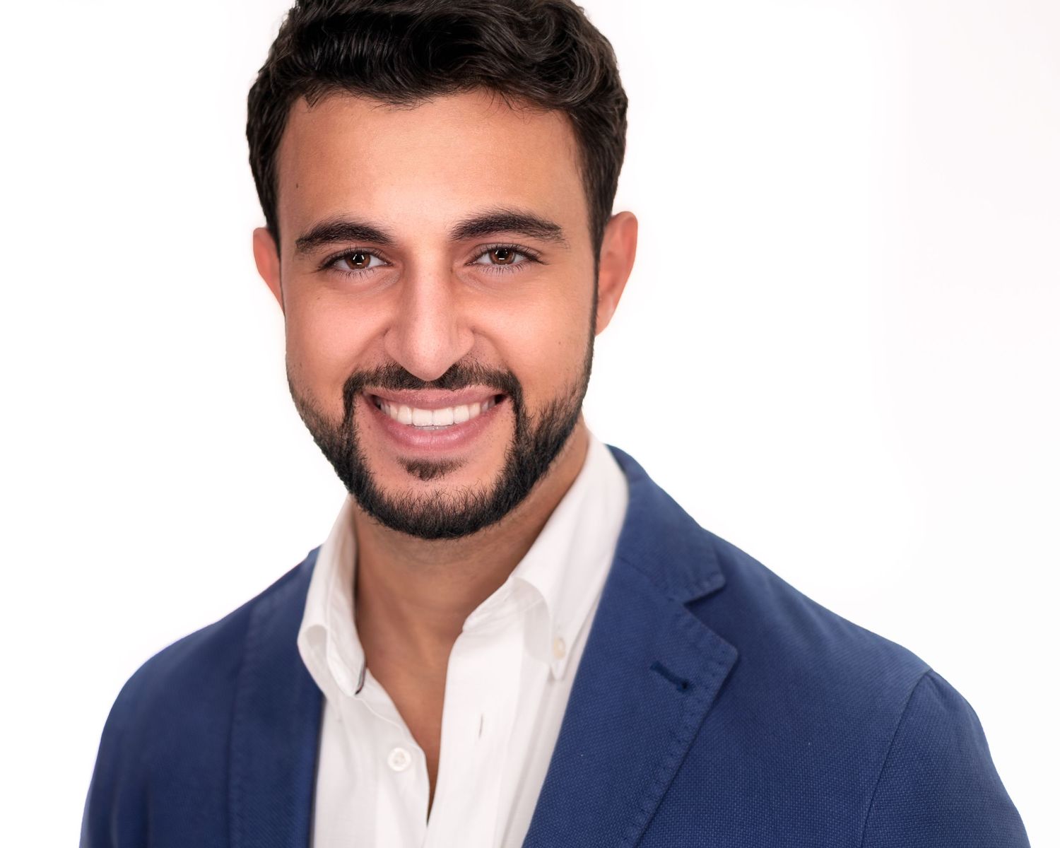 Professional headshot of a person in a navy suit and white shirt against a light background.