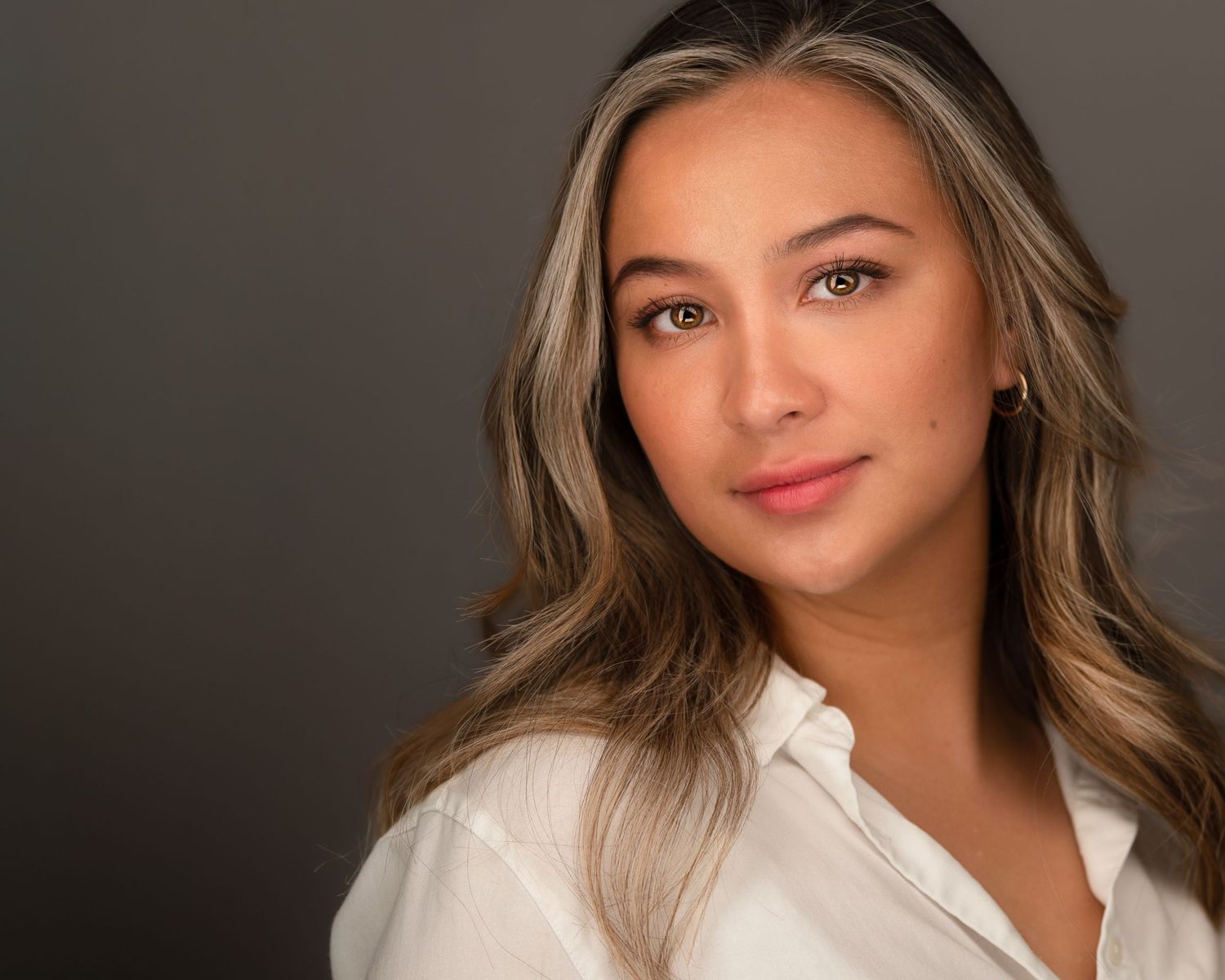 Professional headshots of woman in white collared shirt with wavy hair against dark background.