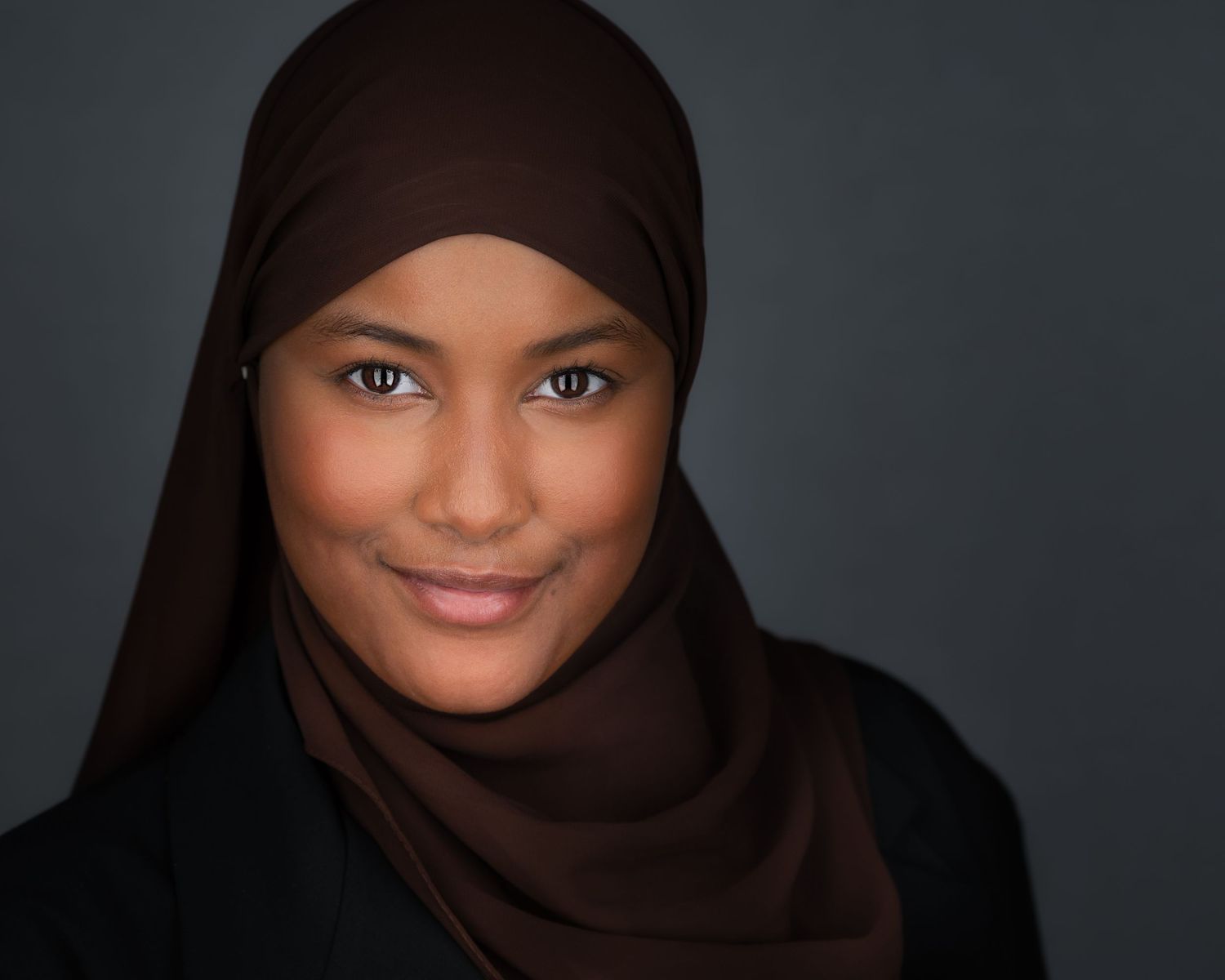 Portrait series showing person wearing black hijab against dark studio background.