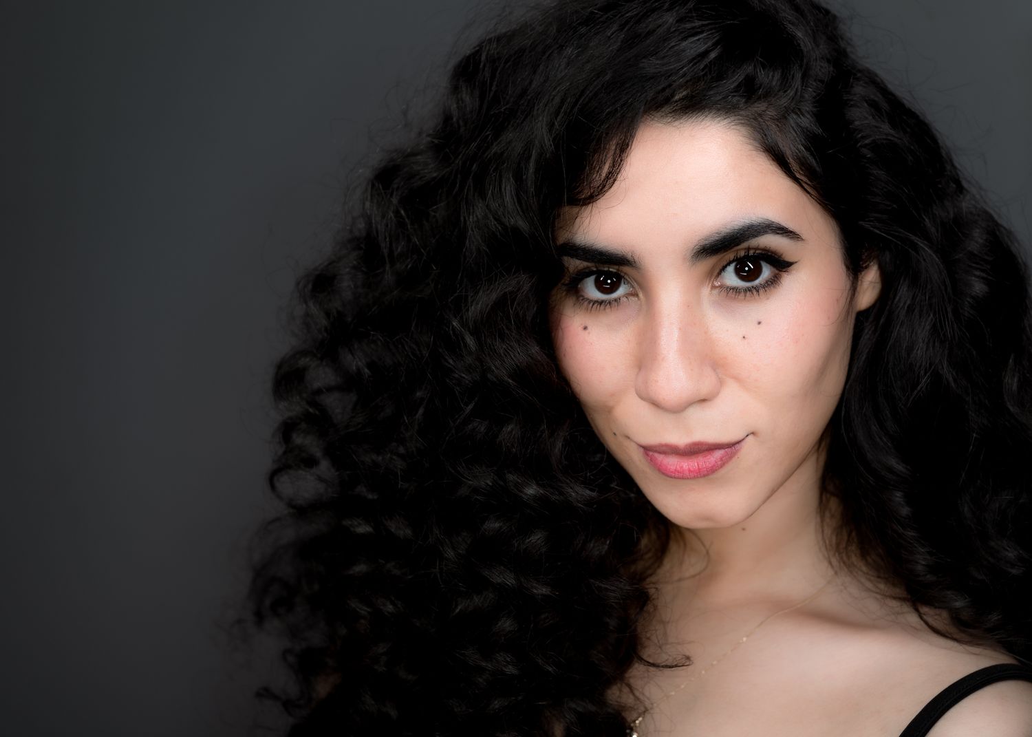 Series of dramatic portrait shots showing dark curly hair against a black background.