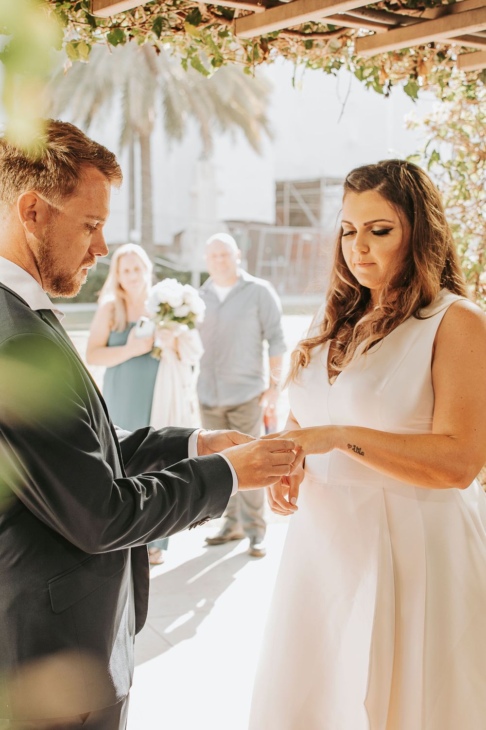 Wedding couple sharing intimate moments under floral decorations at an outdoor venue.
