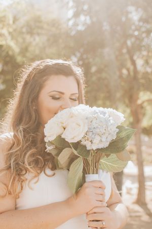Bride holding white rose bouquet in dreamy golden sunlight.
