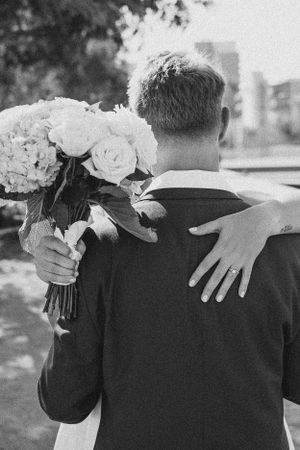 Black and white series showing embrace with white floral bouquet.