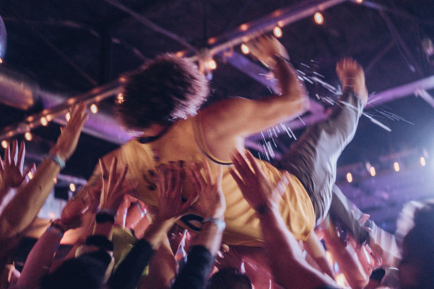 Andy Frasco, a musician, crowd surfing, while a liquid is being sprayed (beer, probably)