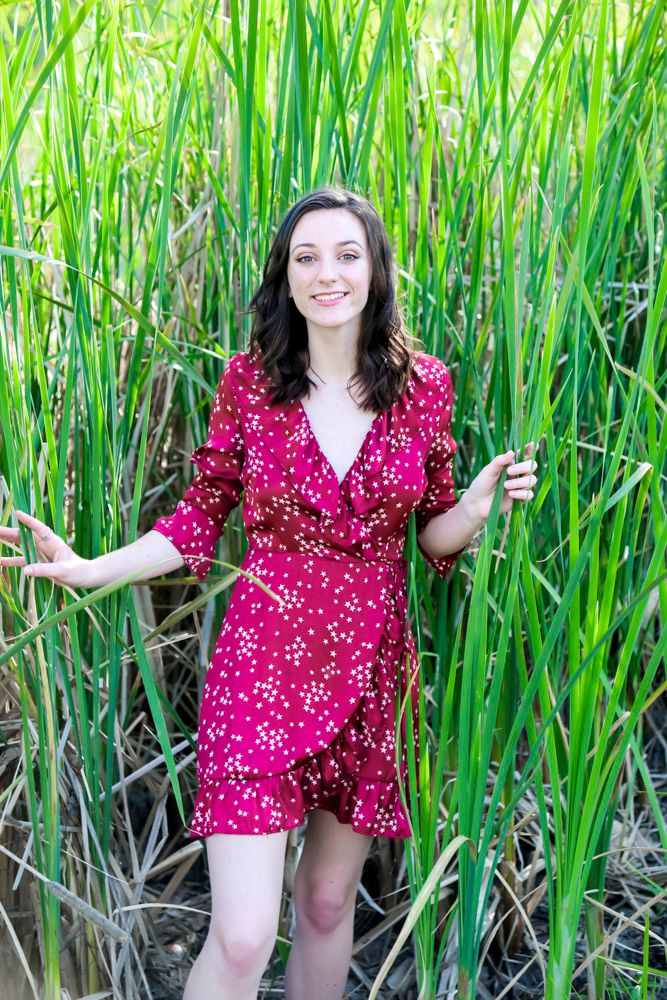 senior in red dress coming out of the reeds in elk grove, california