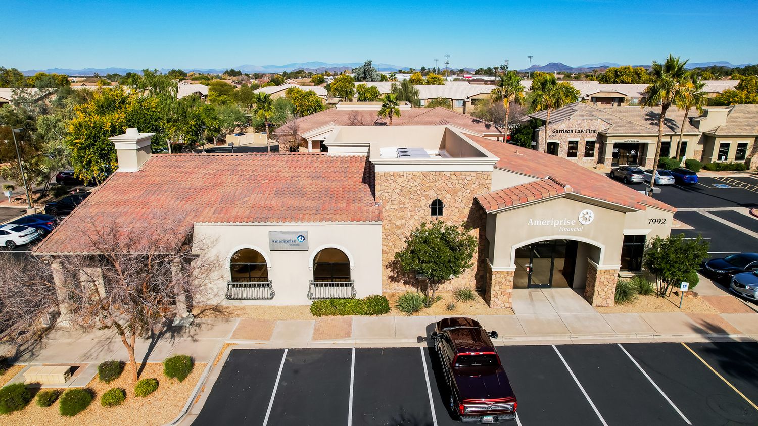 Aerial view of suburban neighborhood with residential homes and parking lots in a desert landscape.