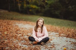 Casual outdoor portraits on fallen autumn leaves with golden trees in background.