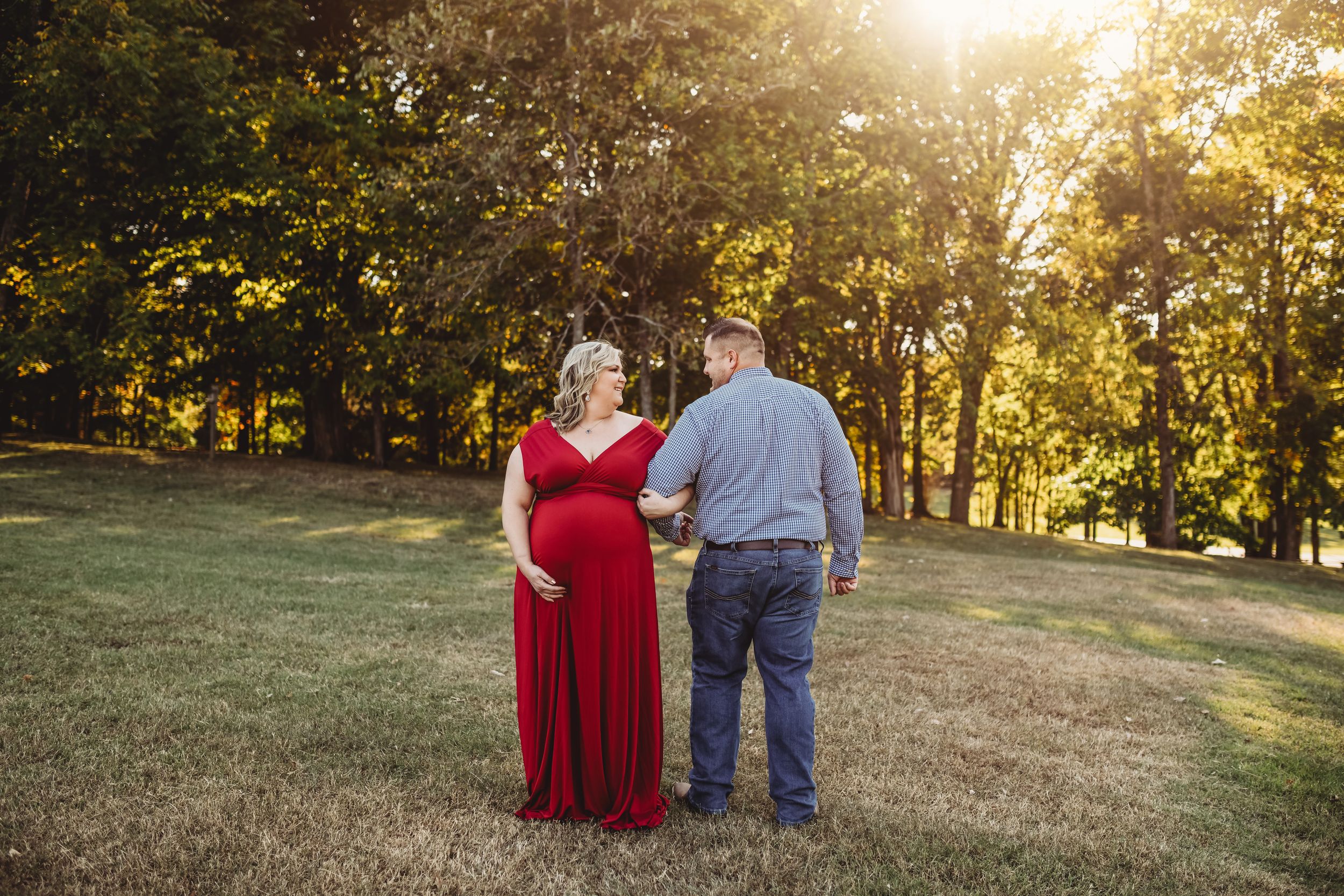 A couple shares an intimate moment in a park during golden hour photography session.