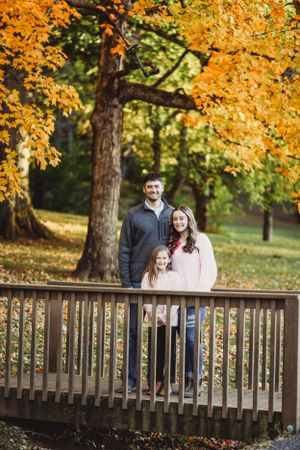 Group portrait on wooden bridge with stunning golden autumn trees in background.