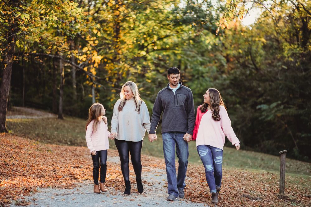 Group strolling through a park during fall with colorful autumn foliage overhead.