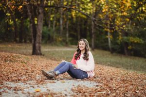 People enjoying a casual autumn day on fallen leaves in a wooded park setting.