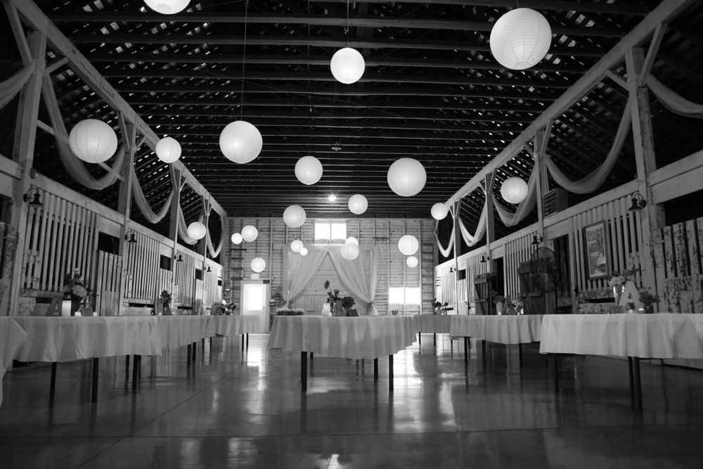A black and white photo of an elegant barn reception hall with hanging paper lanterns.