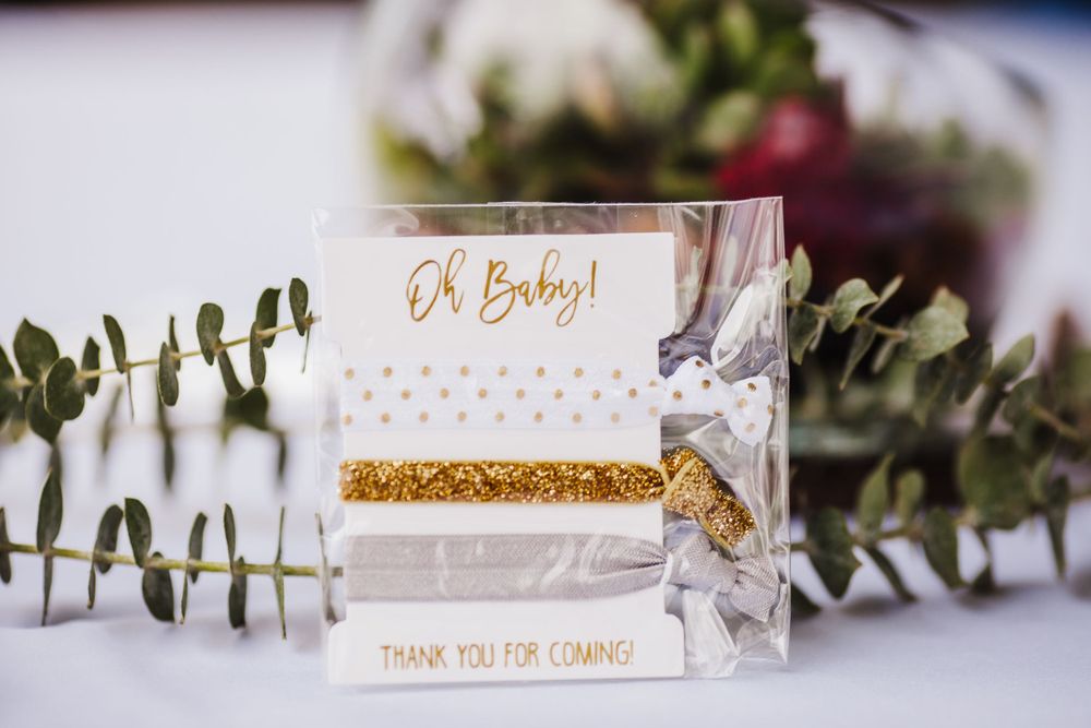 A gold-accented baby shower invitation card with eucalyptus leaves as decoration.