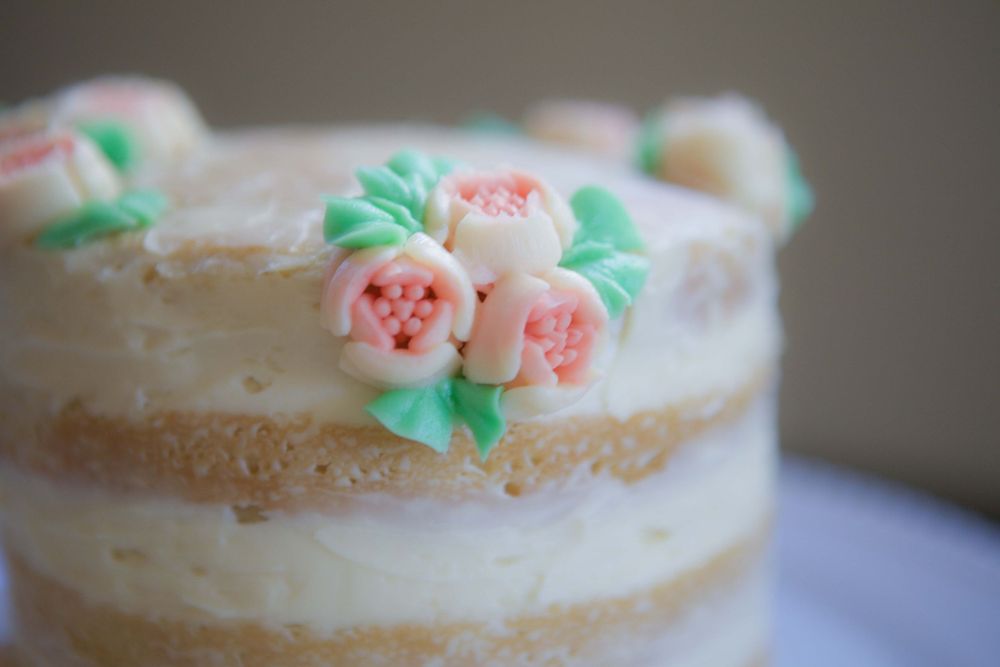 Close-up of white layer cake decorated with delicate mint green and pink sugar flowers.
